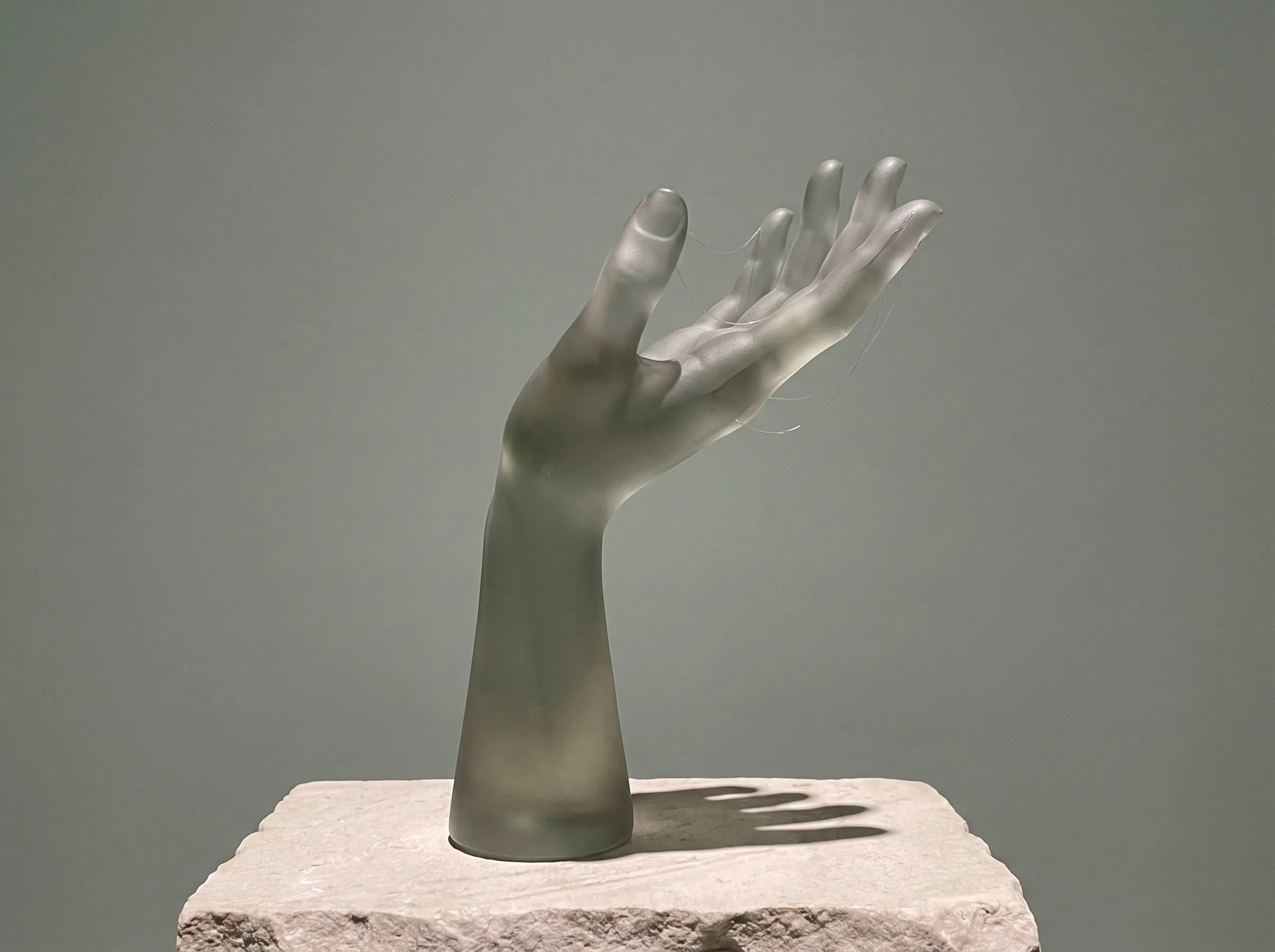 A sculptural translucent hand making a relaxed gesture. Conceptual artwork.